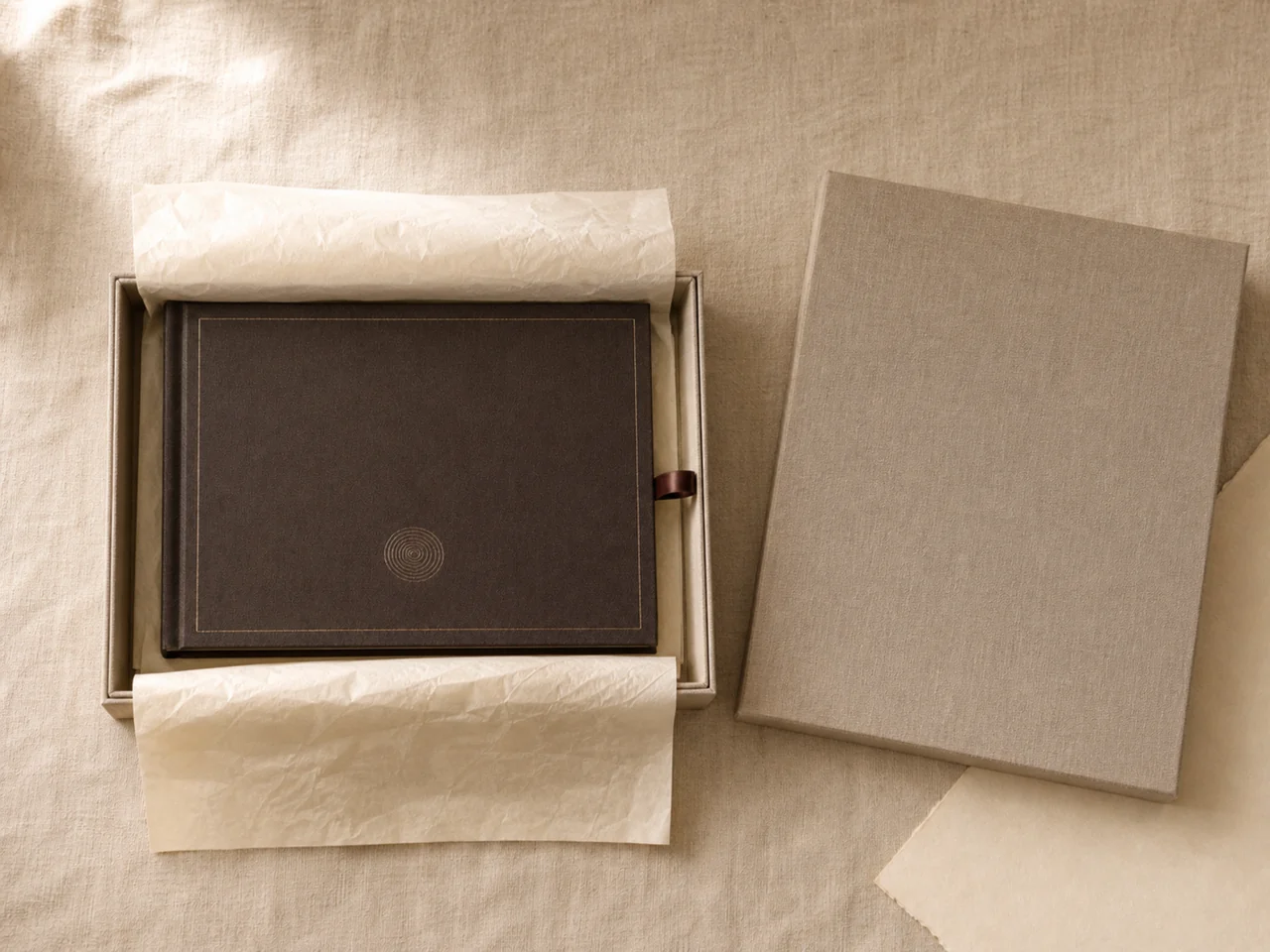 A dark cloth hardcover resting in its open gift box on tissue, the lid placed alongside.